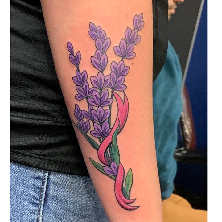 Neo-traditional flower design on the back of a forearm. Sprigs of lavendar with a pink ribbong entertwined