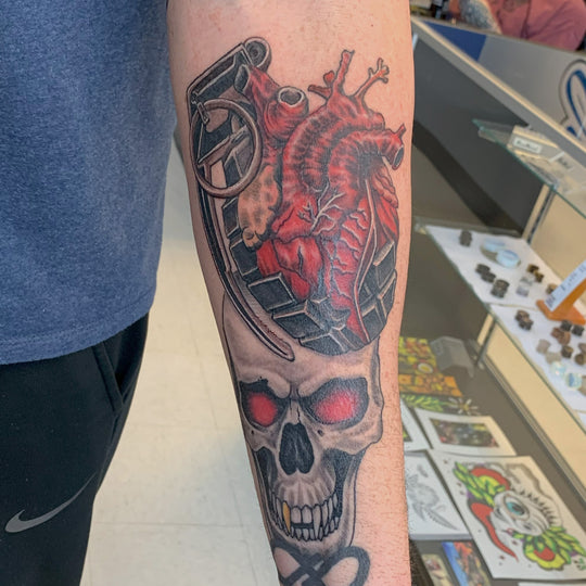 Black and grey with red tattoo of a skull and grenade morphing into an anatomical heart