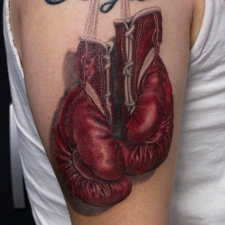 Realistic tattoo of red boxing gloves.