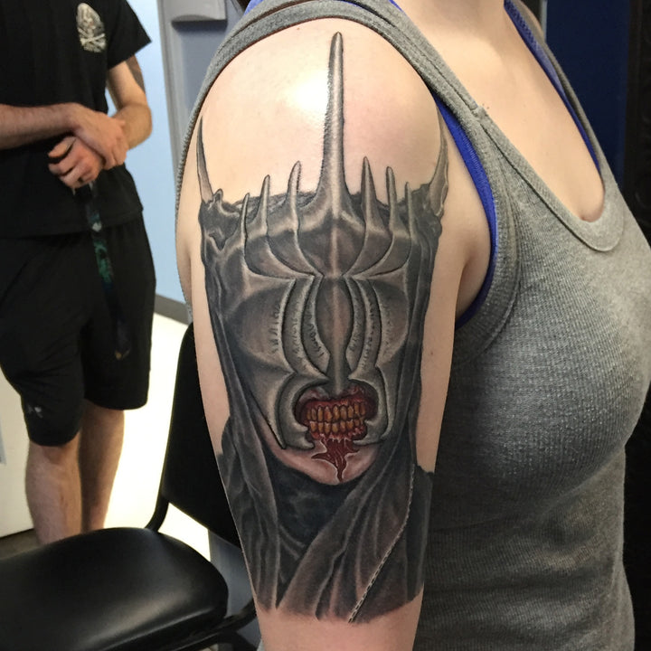 Realistic color portrait of the Mouth of Sauron on a woman's upper arm.