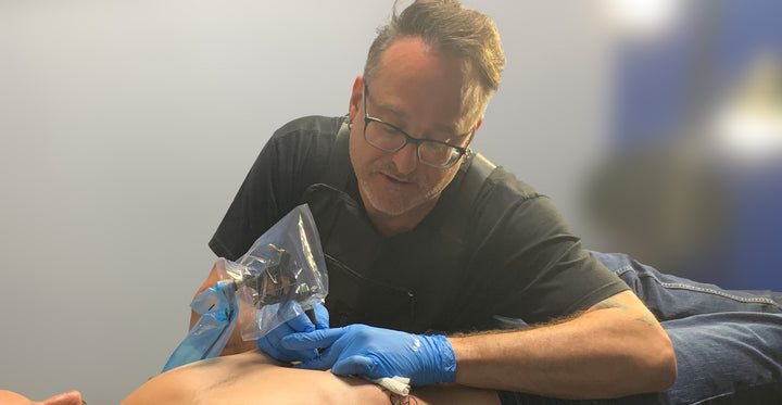 Artist Shawn Pierce tattooing a mans Stomach