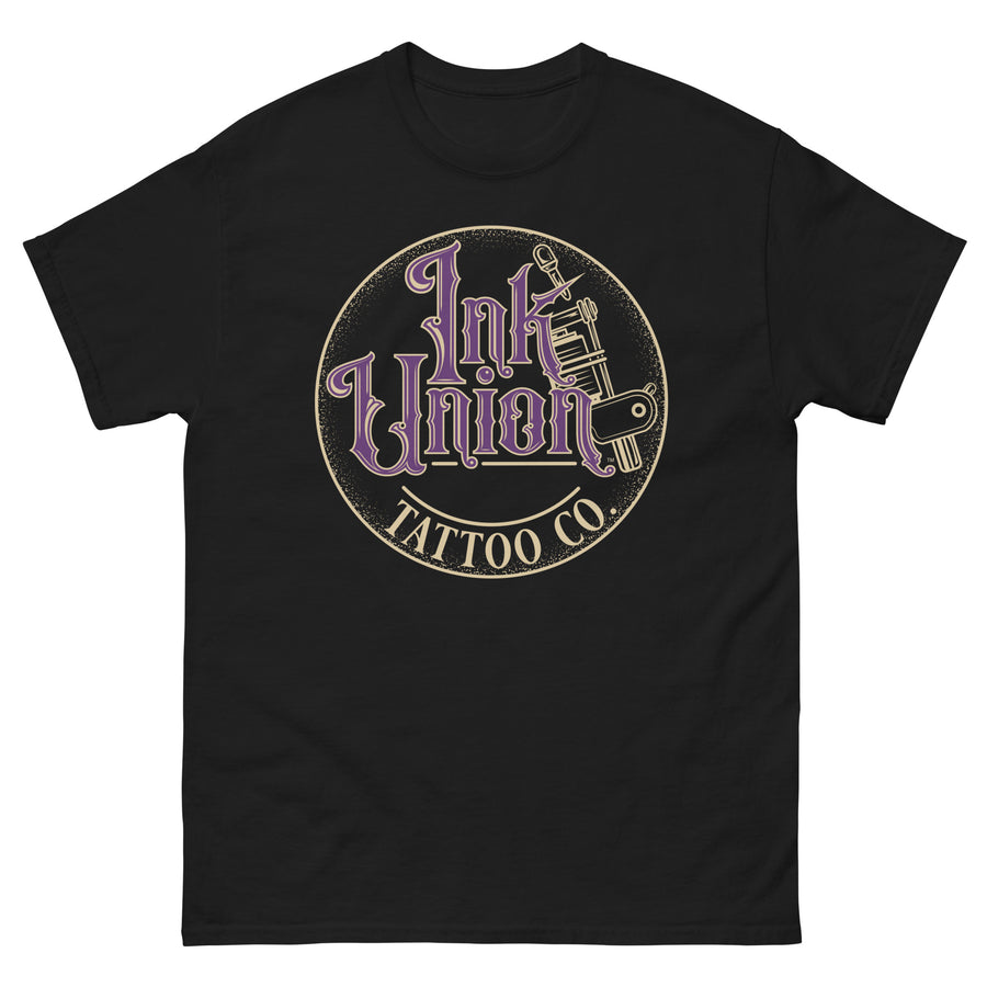A black t-shirt with a gold circle containing fancy lettering in purple and gold that says Ink Union and a gold tattoo machine peeking out from behind on the right side.  There is a dot work gradient inside the circle, and the words Tattoo Co. in gold are at the bottom of the design.