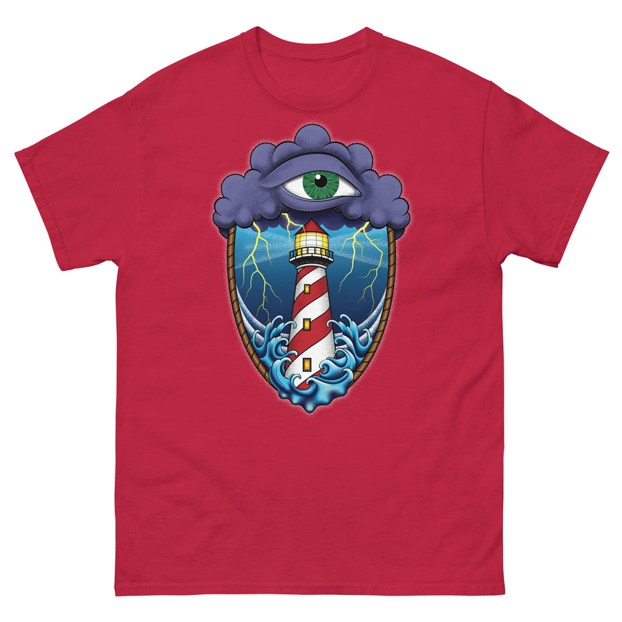 A cardinal red t-shirt with an old school eye of the storm tattoo design of large dark purple storm clouds at the top of the design with a green eye in the middle of the clouds.  Below the clouds is an oval shape with brown rope. Inside the rope are stormy seas and a lighthouse with lightning striking in the background.  At the bottom of the design, some of the waves are spilling out of the rope barrier. The sky and seas are hues of blue; the lighthouse is white and red striped like a barber pole.