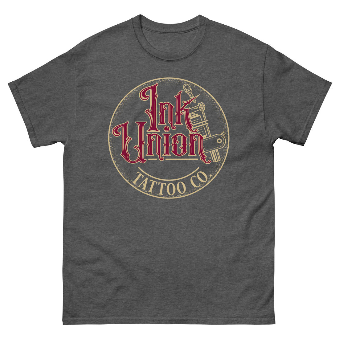 A dark grey t-shirt with a gold circle containing fancy lettering in red and gold that says Ink Union and a gold tattoo machine peeking out from behind on the right side. There is a dot work gradient inside the circle, and the words Tattoo Co. in gold are at the bottom of the design.