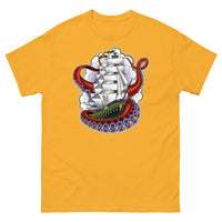 A yellow t-shirt with an old-school clipper ship tattoo design in green and brown with white sails surrounded by octopus tentacles in shades of red with purple tentacles. Behind the ship are purple-tinged clouds.