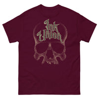A maroon t-shirt with a gold dot work human skull and the words Ink Union in fancy gold and black lettering across the forehead of the skull.