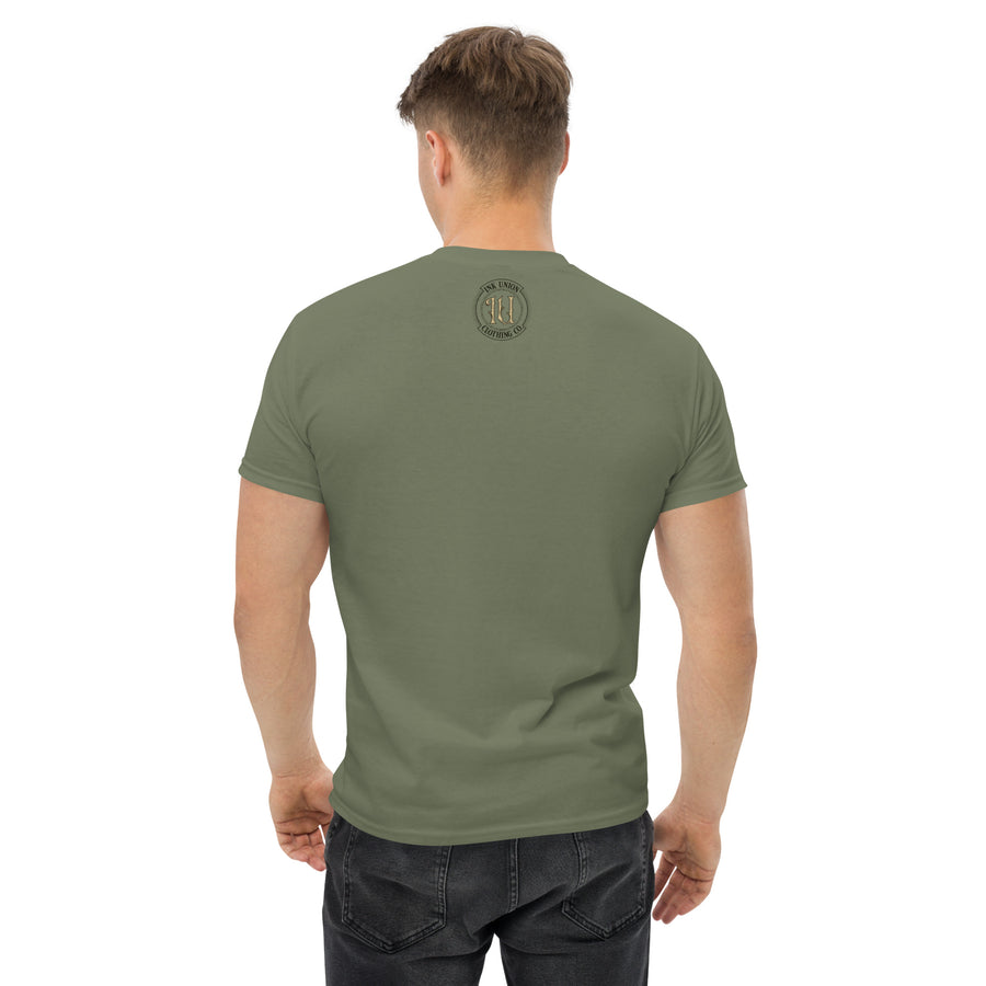 The rear view of an attractive man wearing a military green t-shirt with a small gold and black Ink Union badge logo centered just under the neckline. 