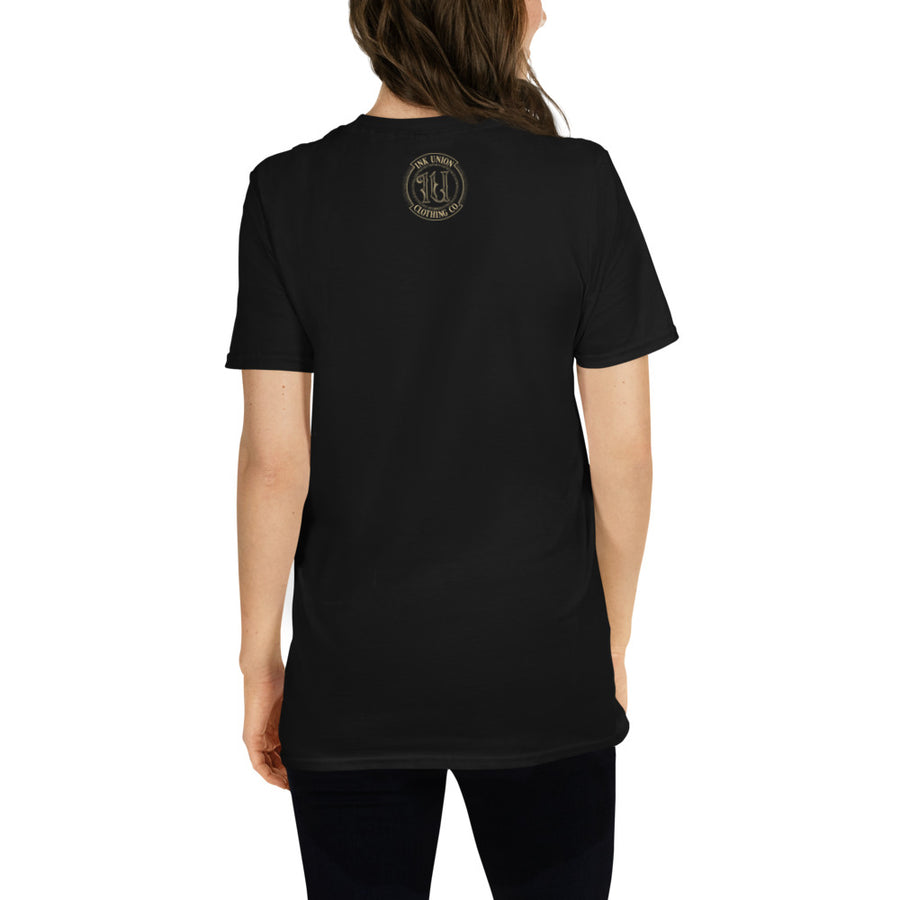 The back view of a woman wearing a black t-shirt with a small gold Ink Union Badge Logo centered just under the neckline.