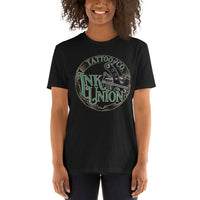 An attractive woman wearing a black t-shirt adorned with the Ink Union Tattoo Co. green and gold with a silver tattoo machine logo.