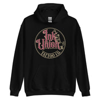 A black hoodie with a gold circle containing fancy lettering in red and gold that says Ink Union and a gold tattoo machine peeking out from behind on the right side.  There is a dot work gradient inside the circle, and the words Tattoo Co. in gold are at the bottom of the design.
