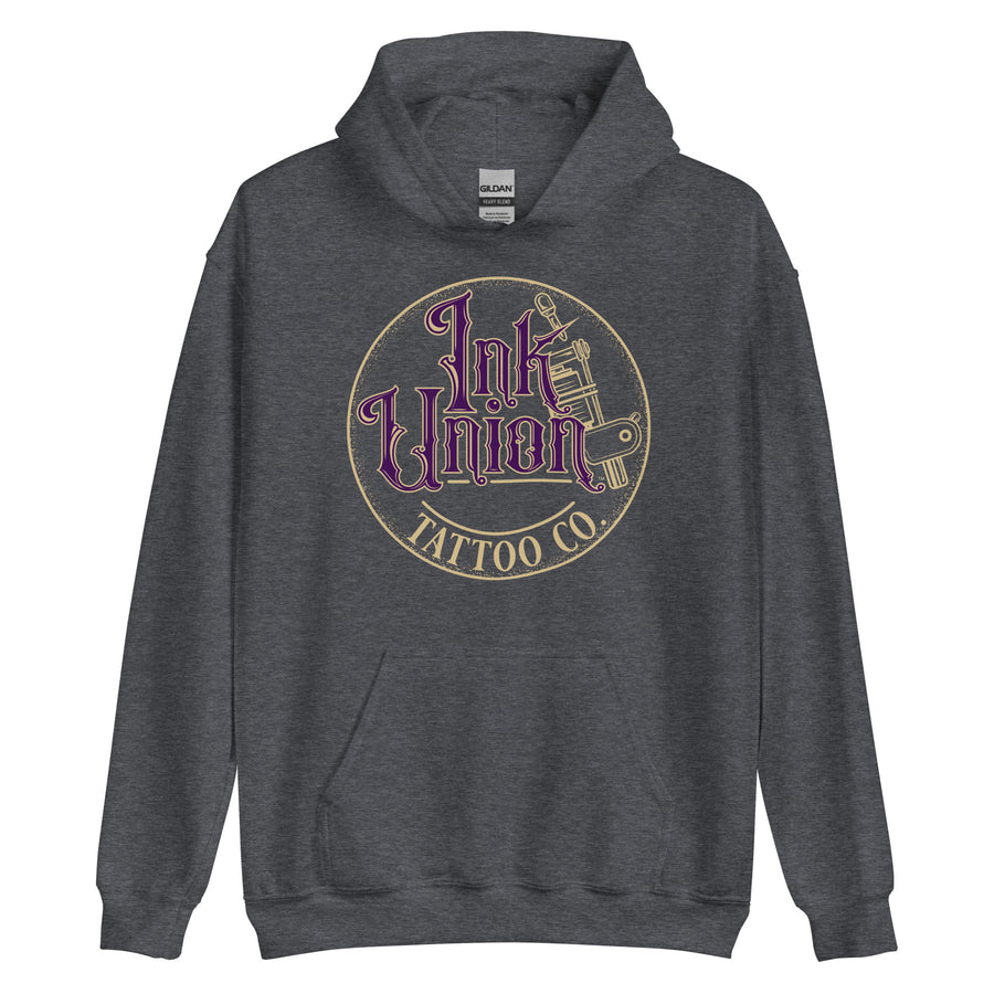 A dark grey hoodie with a gold circle containing fancy lettering in purple and gold that says Ink Union and a gold tattoo machine peeking out from behind on the right side.  There is a dot work gradient inside the circle, and the words Tattoo Co. in gold are at the bottom of the design.