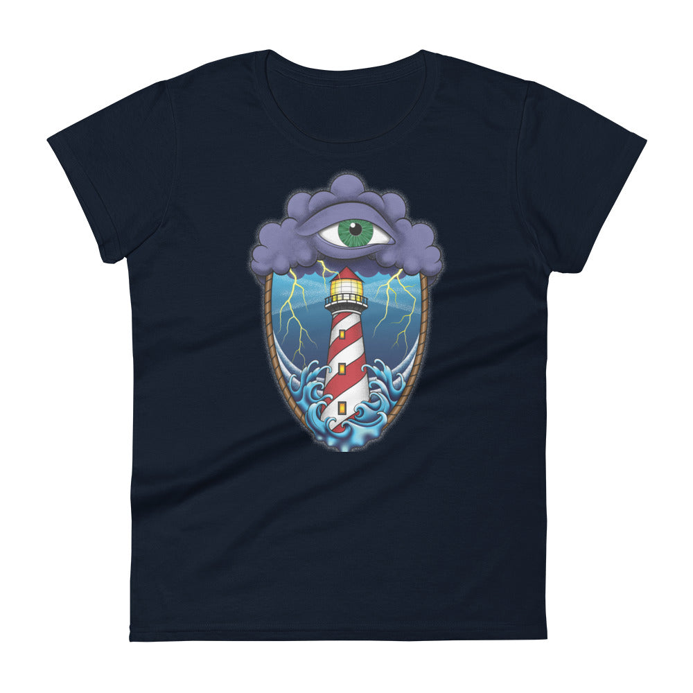 A navy blue t-shirt with an old school eye of the storm tattoo design of large dark purple storm clouds at the top of the design with a green eye in the middle of the clouds.  Below the clouds is an oval shape with brown rope. Inside the rope are stormy seas and a lighthouse with lightning striking in the background.  At the bottom of the design, some of the waves are spilling out of the rope barrier. The sky and seas are hues of blue; the lighthouse is white and red striped like a barber pole.