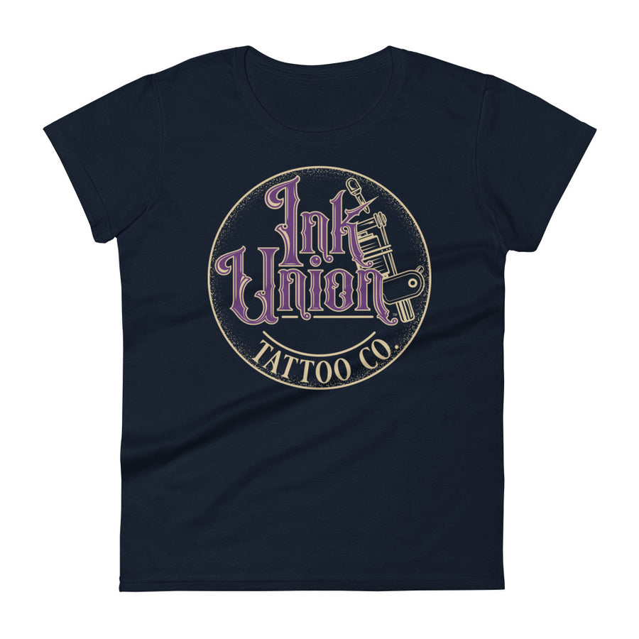 A navy blue t-shirt with a gold circle containing fancy lettering in purple and gold that says Ink Union and a gold tattoo machine peeking out from behind on the right side.  There is a dot work gradient inside the circle, and the words Tattoo Co. in gold are at the bottom of the design.