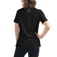 The back view of an attractive woman wearing a black t-shirt with a small gold Ink Union Badge Logo centered just under the neckline.