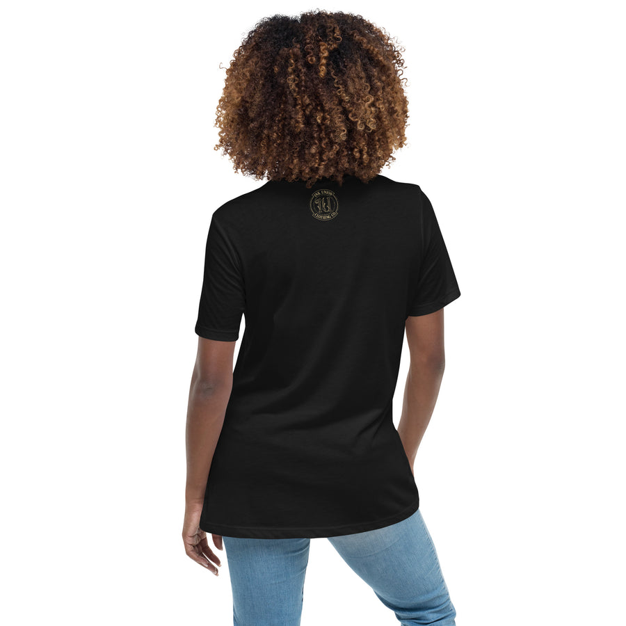 The back view of a woman wearing a black t-shirt with a small gold Ink Union Badge Logo centered just under the neckline.