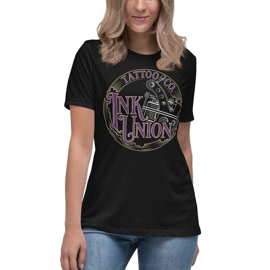 An attractive woman wearing a black t-shirt adorned with the Ink Union Tattoo Co. purple and gold with a silver tattoo machine logo.