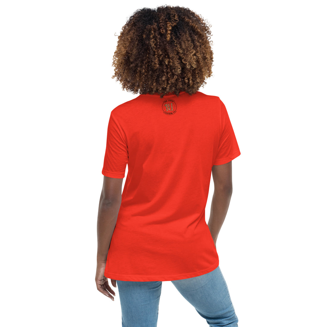 The back view of an attractive woman wearing a poppy red  t-shirt with a small gold and black Ink Union badge Logo centered just under the neckline.