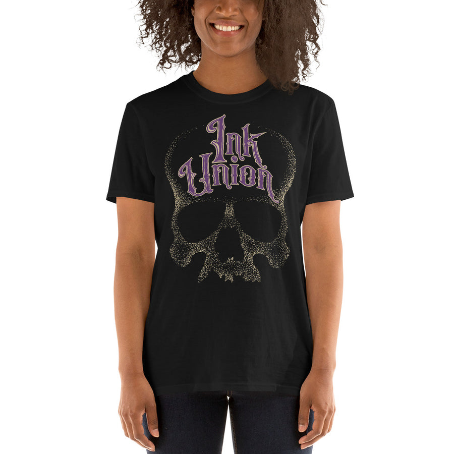 woman wearing an Ink Union Clothing Co. unisex black t-shirt  featuring a large dot work gold skull centered on the shirt and Ink Union in large fancy gold and purple script across the forehead of the skull